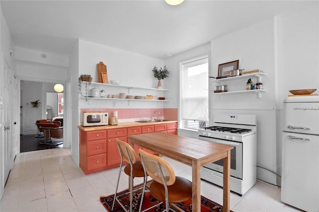 kitchen featuring backsplash, white appliances, and sink