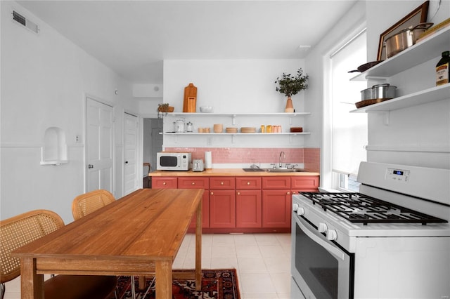 kitchen with light tile patterned flooring, white appliances, and sink