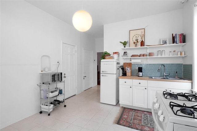 kitchen with pendant lighting, white appliances, white cabinets, sink, and decorative backsplash