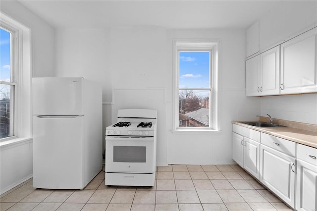 kitchen featuring white cabinets, white appliances, light tile patterned flooring, and sink