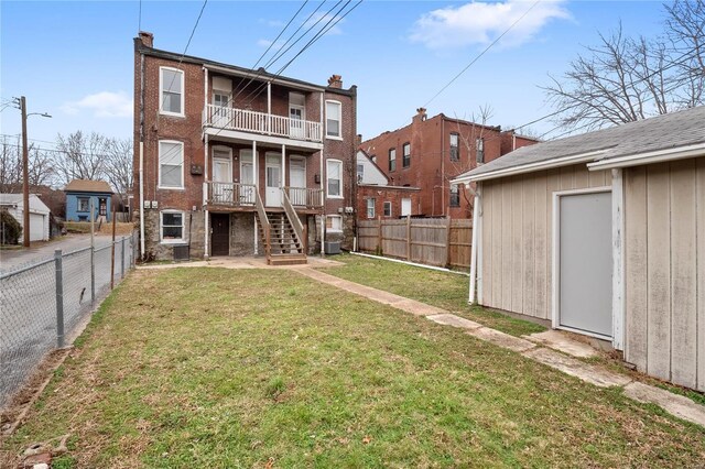 back of property with a balcony and a lawn