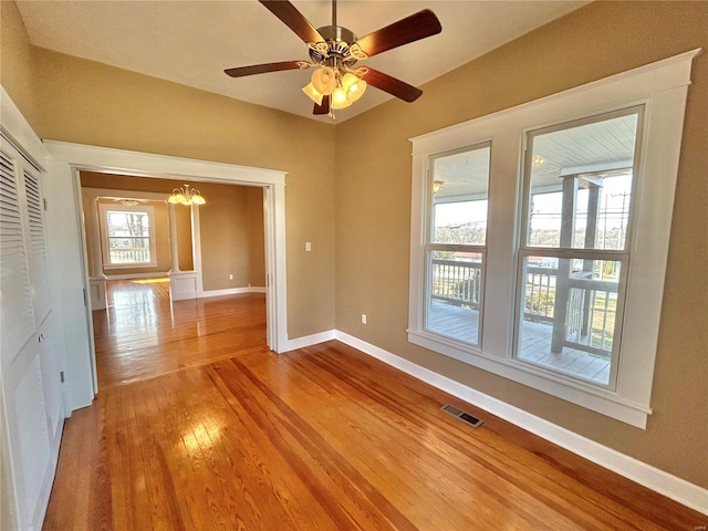 spare room featuring light hardwood / wood-style flooring and ceiling fan with notable chandelier