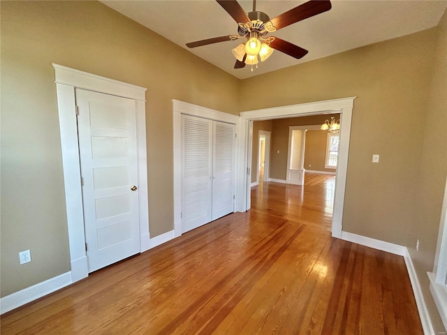 unfurnished bedroom with hardwood / wood-style floors and ceiling fan with notable chandelier