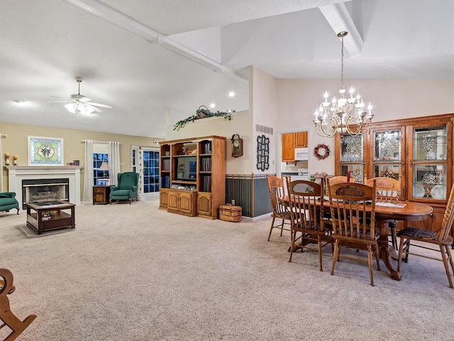 carpeted dining area featuring ceiling fan with notable chandelier and high vaulted ceiling