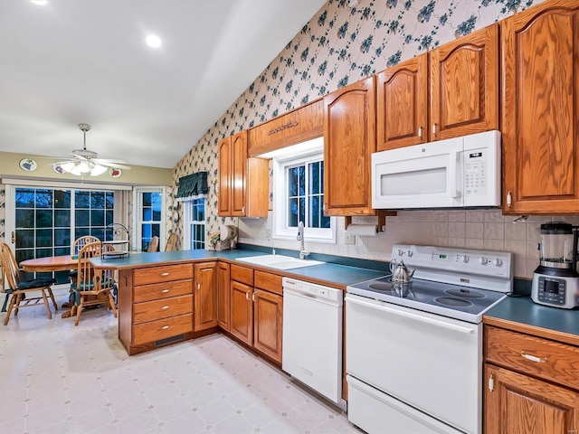 kitchen with white appliances, lofted ceiling, sink, ceiling fan, and kitchen peninsula