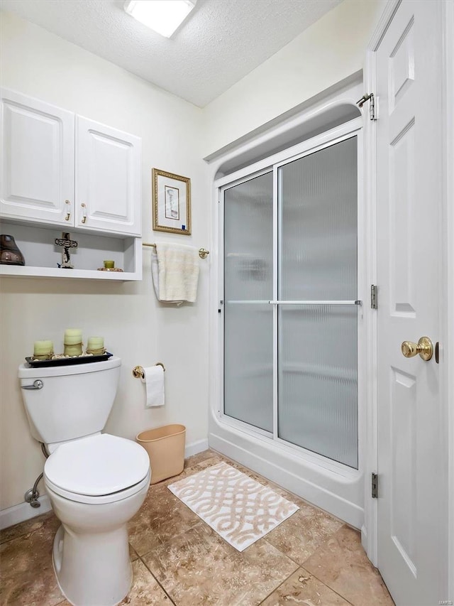 bathroom featuring toilet, a textured ceiling, and walk in shower