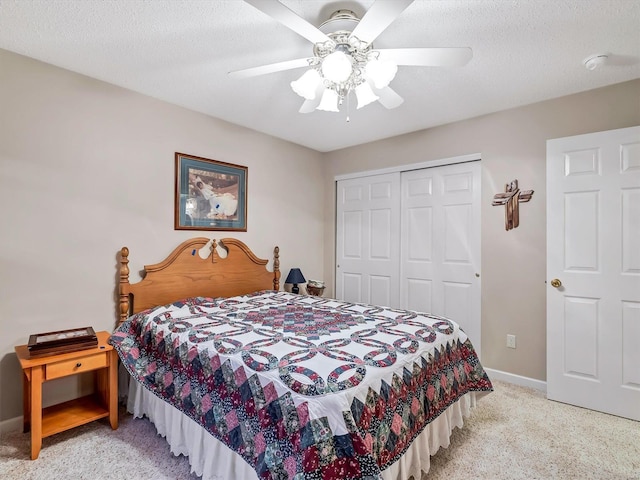 bedroom featuring light carpet, a textured ceiling, a closet, and ceiling fan