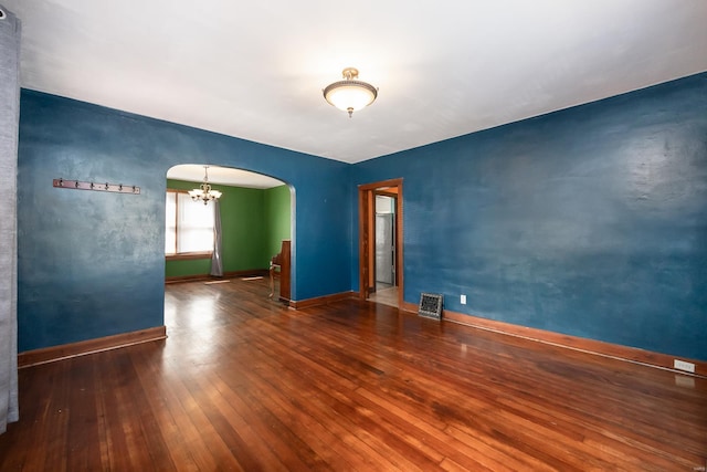 empty room featuring an inviting chandelier and dark wood-type flooring