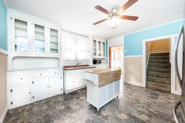 kitchen with wood counters, white refrigerator, sink, ceiling fan, and white cabinetry