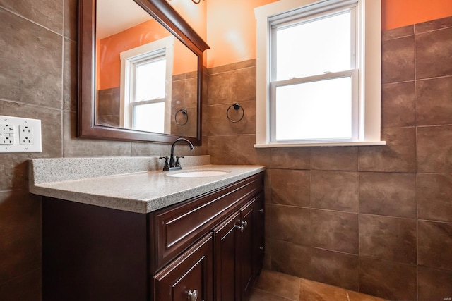 bathroom with vanity, tile patterned floors, tile walls, and a healthy amount of sunlight