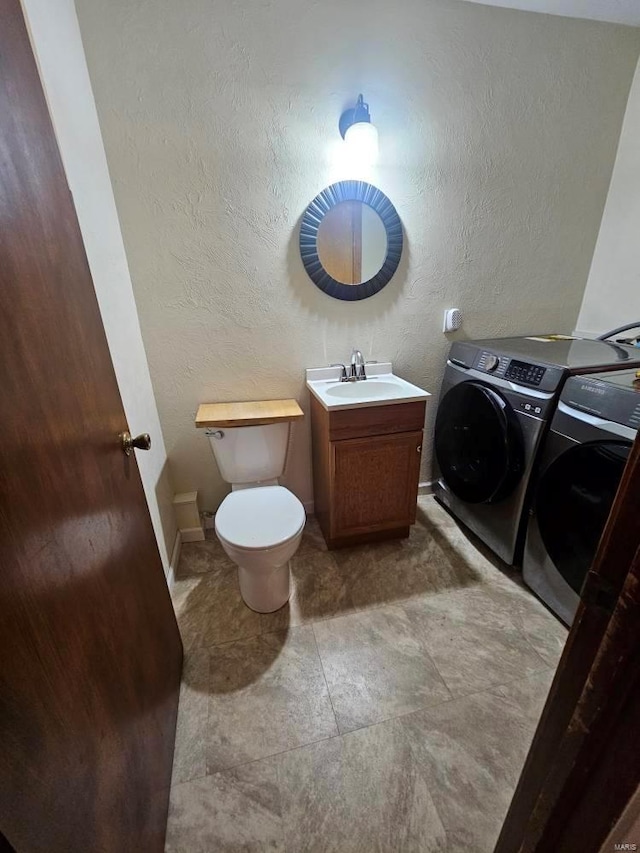 bathroom with tile patterned floors, vanity, toilet, and washing machine and clothes dryer