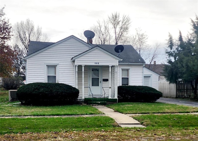 bungalow-style house featuring a front lawn, covered porch, and central AC unit