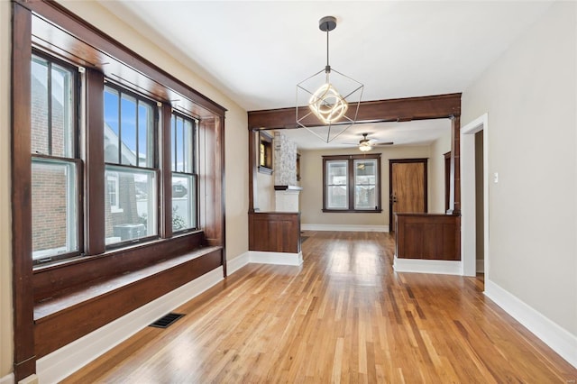 unfurnished dining area featuring plenty of natural light, ceiling fan, and light wood-type flooring