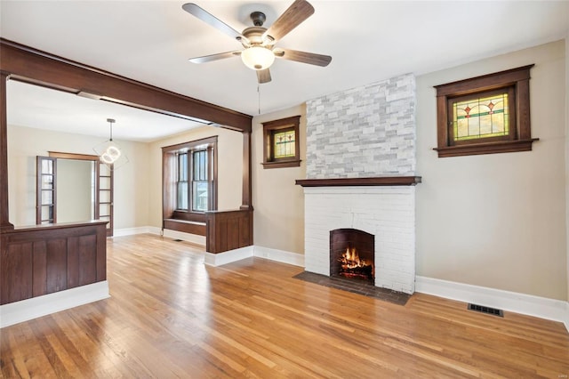 unfurnished living room with a fireplace, ceiling fan, and light hardwood / wood-style flooring