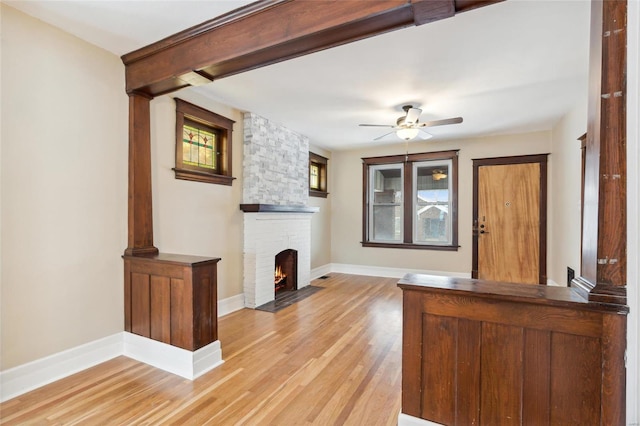 unfurnished living room featuring a fireplace, light hardwood / wood-style flooring, and ceiling fan