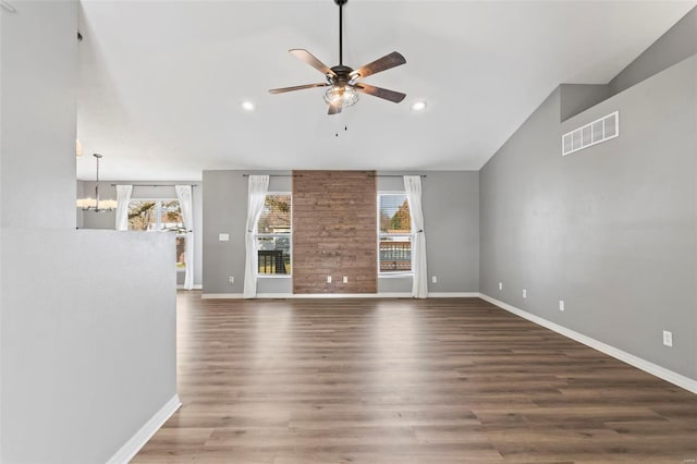 unfurnished living room featuring hardwood / wood-style floors, ceiling fan with notable chandelier, and vaulted ceiling