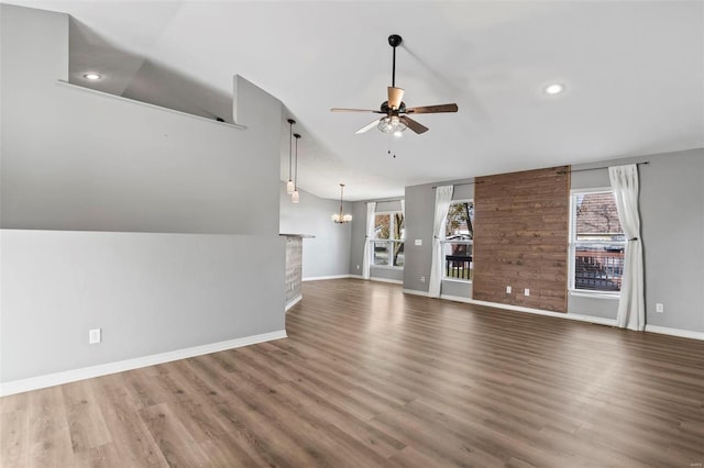 unfurnished living room with lofted ceiling, dark hardwood / wood-style flooring, and ceiling fan with notable chandelier