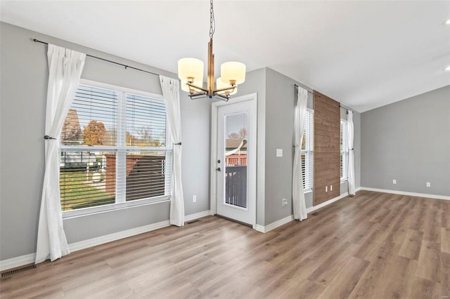 entrance foyer featuring wood-type flooring, a wealth of natural light, and an inviting chandelier