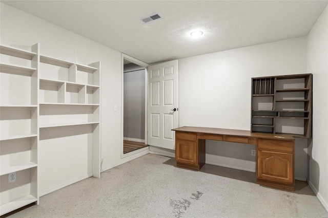 unfurnished office featuring built in desk and a textured ceiling