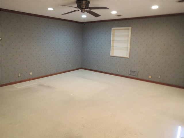 empty room featuring built in shelves, ceiling fan, ornamental molding, and carpet flooring