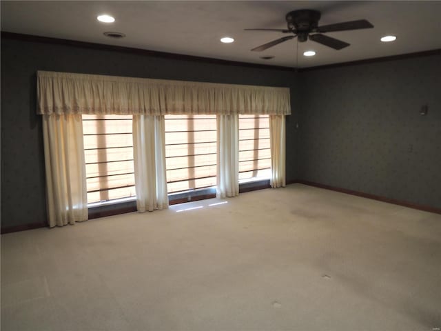 empty room with ornamental molding, plenty of natural light, carpet flooring, and ceiling fan