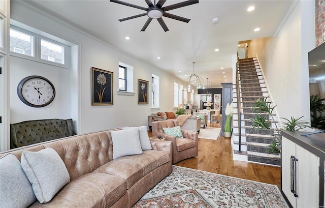 living room with hardwood / wood-style floors, ceiling fan with notable chandelier, and ornamental molding