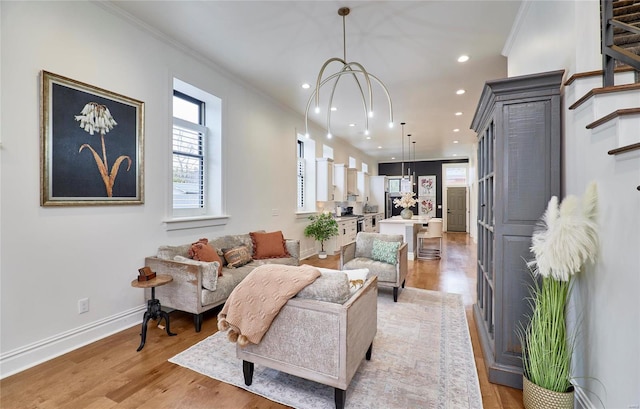 living room featuring light hardwood / wood-style floors, ornamental molding, and an inviting chandelier