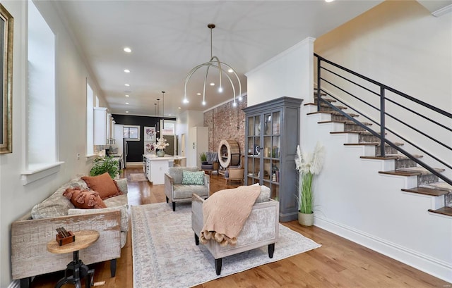 living room with a fireplace, light hardwood / wood-style flooring, crown molding, and a notable chandelier