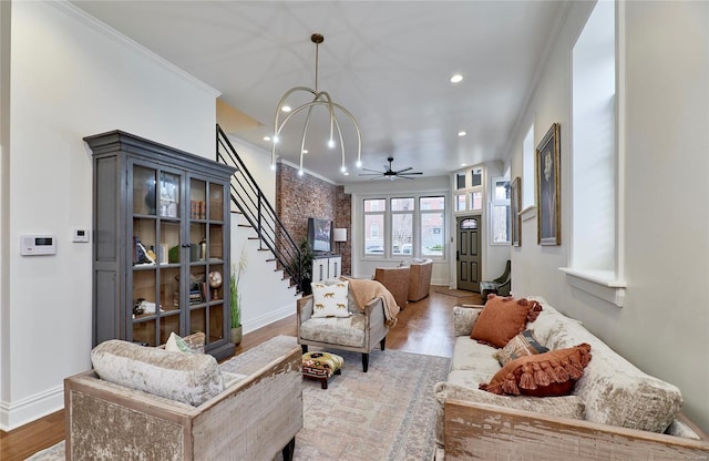 living room with ceiling fan with notable chandelier, hardwood / wood-style flooring, and ornamental molding