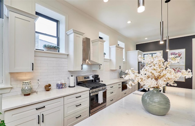 kitchen featuring tasteful backsplash, wall chimney exhaust hood, crown molding, stainless steel range with gas cooktop, and hanging light fixtures