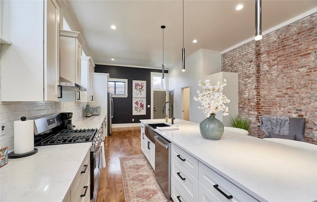 kitchen featuring pendant lighting, stainless steel appliances, light stone counters, and hardwood / wood-style floors