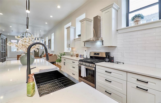 kitchen with white cabinets, pendant lighting, gas range, and wall chimney exhaust hood