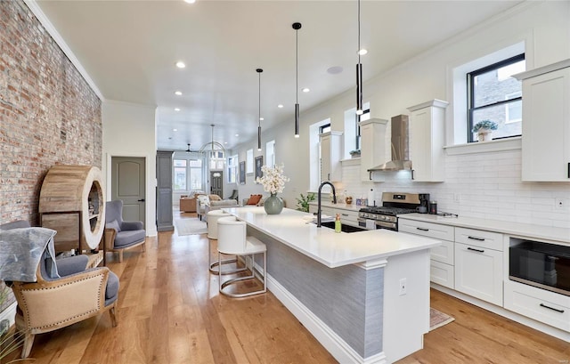 kitchen with sink, stainless steel range with gas cooktop, a wealth of natural light, and an island with sink