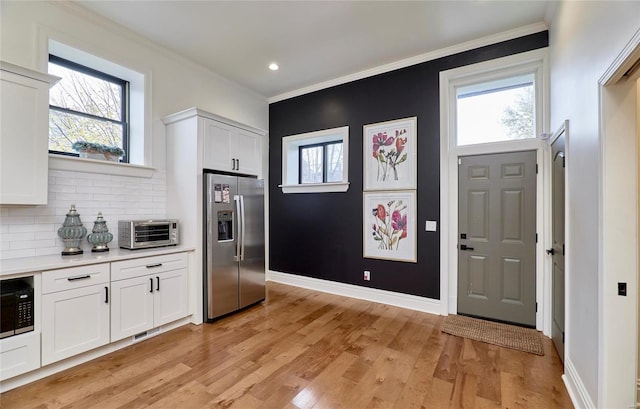 kitchen with stainless steel fridge with ice dispenser, light wood-type flooring, white cabinetry, and a healthy amount of sunlight