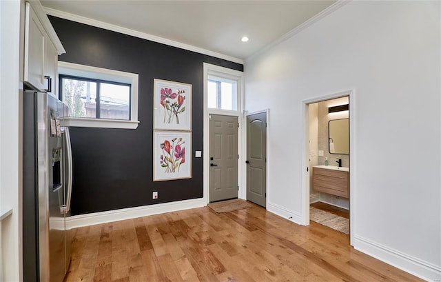 foyer featuring sink, light hardwood / wood-style floors, and ornamental molding