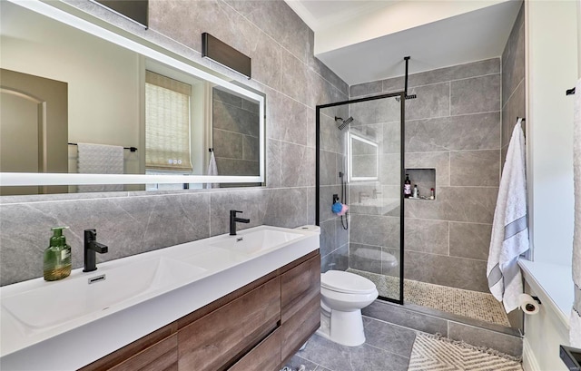 bathroom featuring vanity, a tile shower, backsplash, and toilet