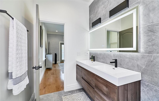 bathroom with hardwood / wood-style flooring, vanity, ornamental molding, and tile walls