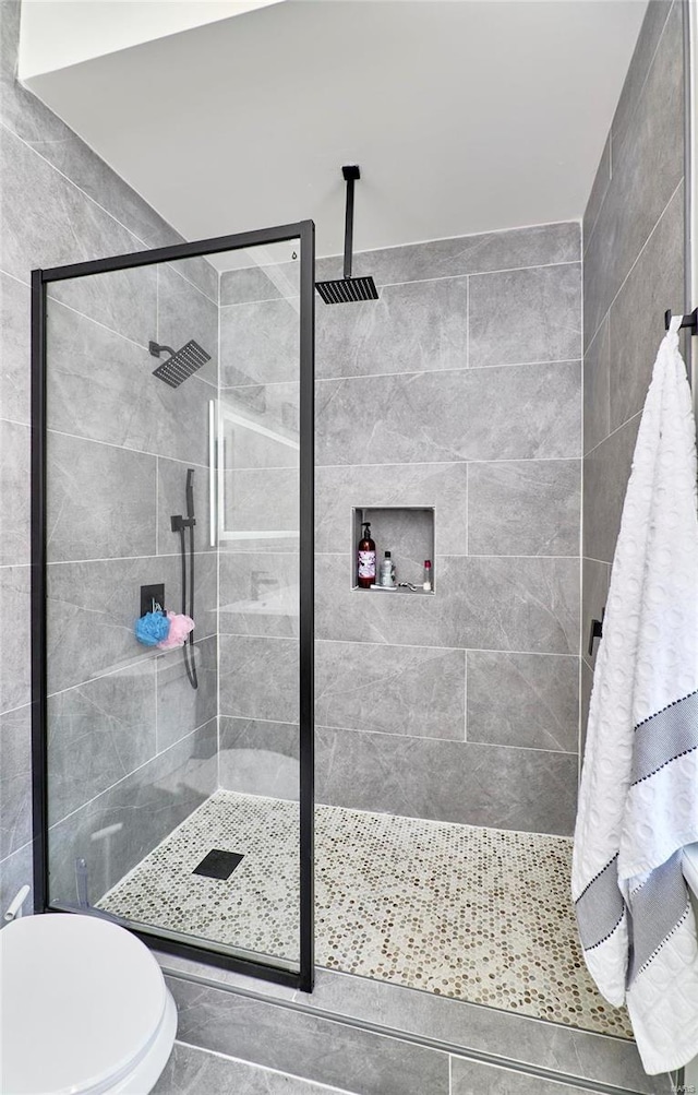 bathroom with tile patterned flooring, toilet, and a shower with door