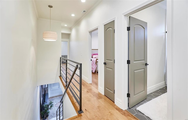 corridor with light hardwood / wood-style floors and ornamental molding