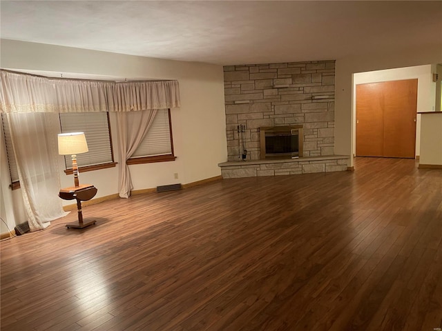 unfurnished living room featuring wood-type flooring and a stone fireplace