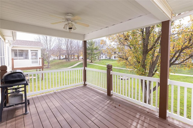 deck featuring ceiling fan, a grill, and a yard