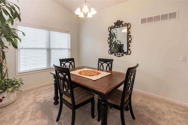 carpeted dining room with lofted ceiling and a chandelier