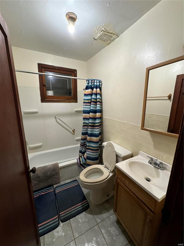 full bathroom featuring shower / bath combo, tile patterned floors, vanity, tile walls, and toilet