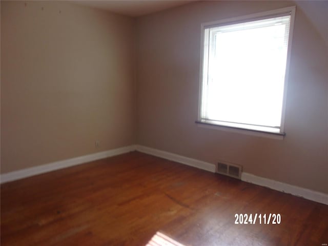 empty room featuring visible vents, baseboards, and wood finished floors