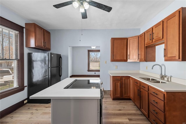 kitchen featuring ceiling fan, sink, electric range, black fridge, and light wood-type flooring