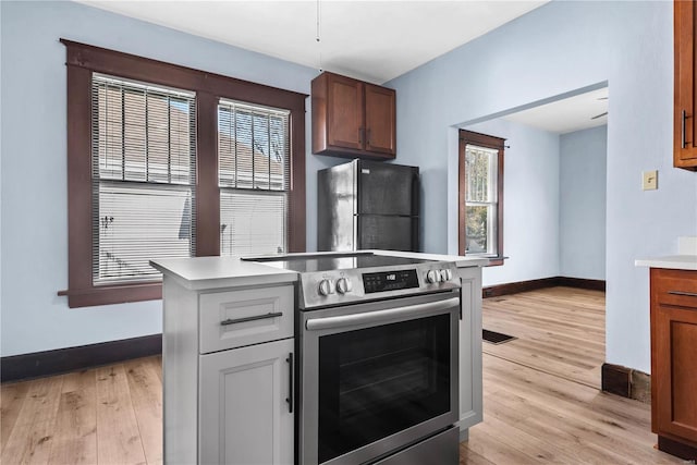 kitchen featuring light wood-type flooring, black fridge, and stainless steel electric range