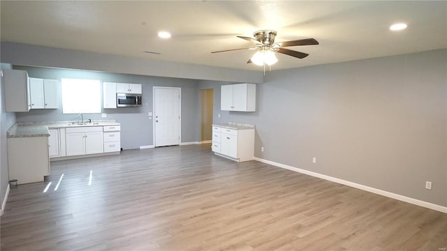 kitchen featuring white cabinets, light hardwood / wood-style floors, ceiling fan, and sink