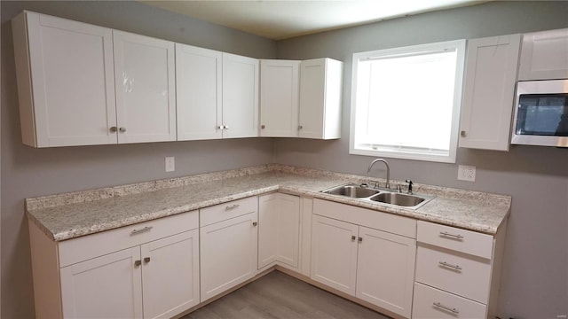 kitchen with white cabinets, light wood-type flooring, and sink