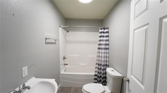 full bathroom with hardwood / wood-style flooring, sink, shower / tub combo, and toilet