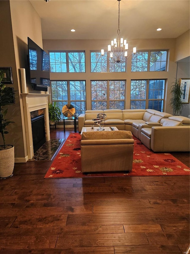 living room with a fireplace, a towering ceiling, dark wood-type flooring, and a notable chandelier